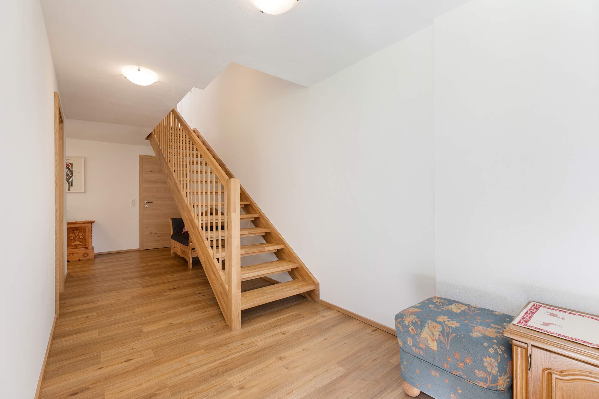 Entree mit Holztreppe zum Koch-, Ess- und Wohnbereich und Terrasse.